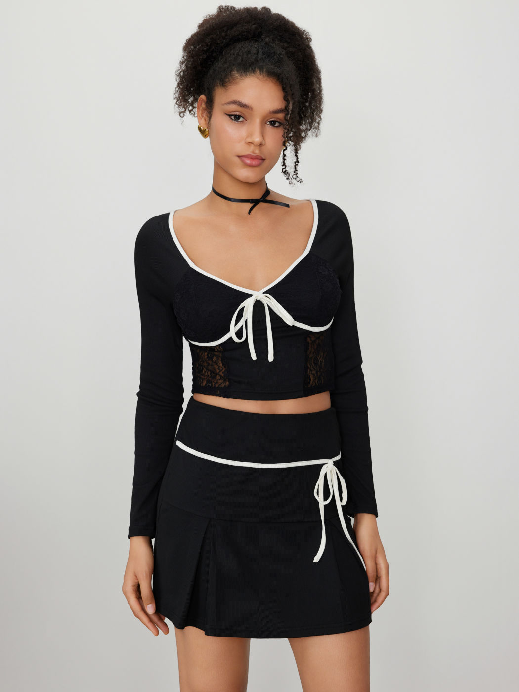 Top corsetto in pizzo con nodo a contrasto e gonna plissettata